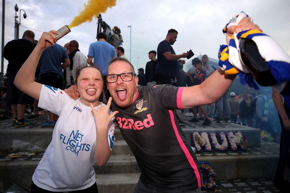 Two fans celebrate with a smoke grenade and scarf