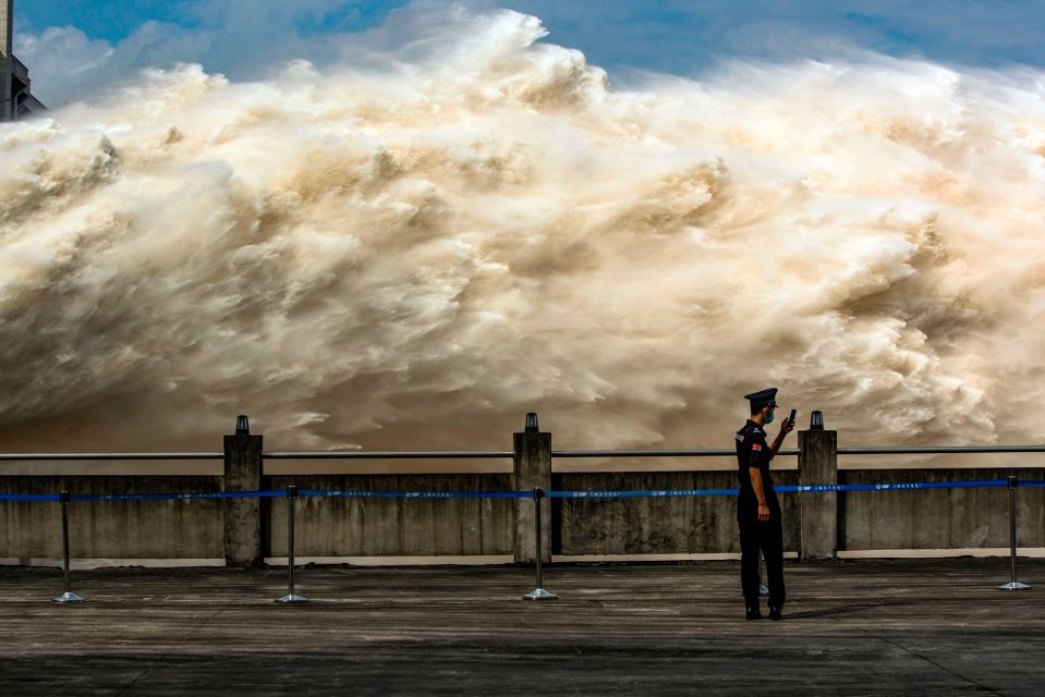 A security guard looking at his smartphone while water is released from the Three Gorges Dam