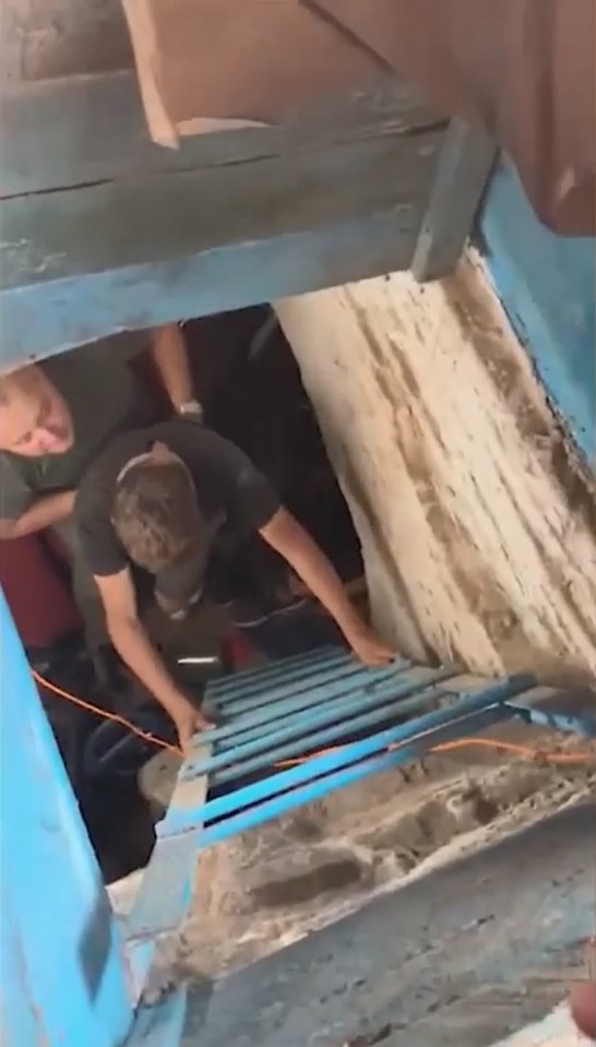 One of the trapped boys, weakened by his sickening experience, is helped up a ladder