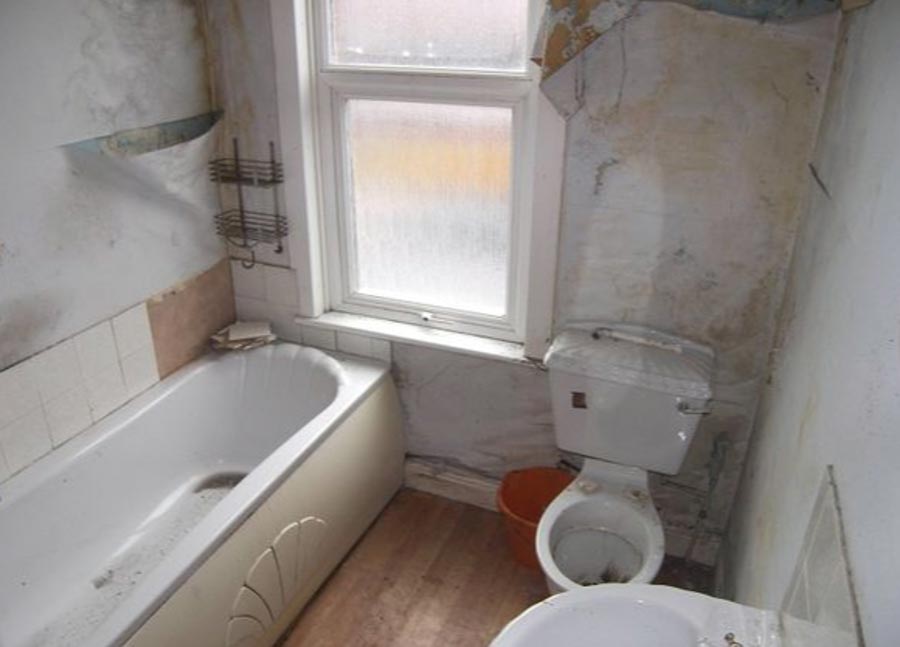 The bathroom is grimy too, with stained walls and a filthy toilet 