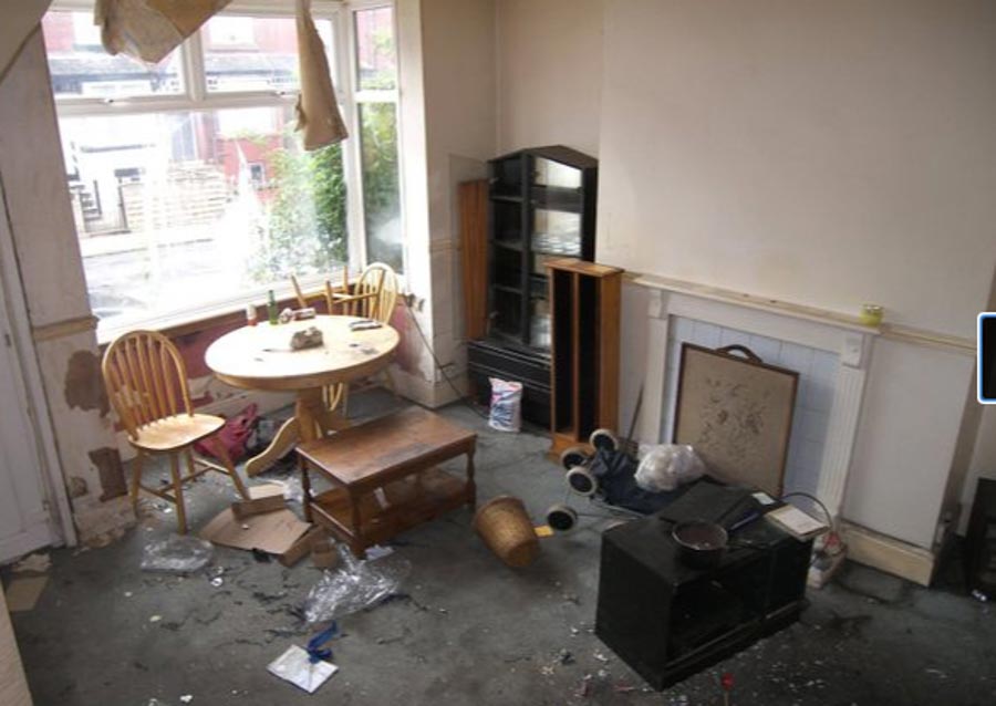 Carpets in the living room are stained, while the current owner has left plenty of junk behind them