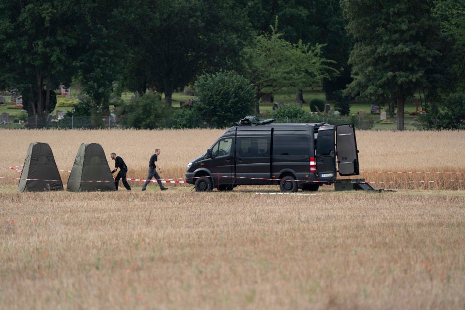 A police van in a field with the fenced off allotments in the background