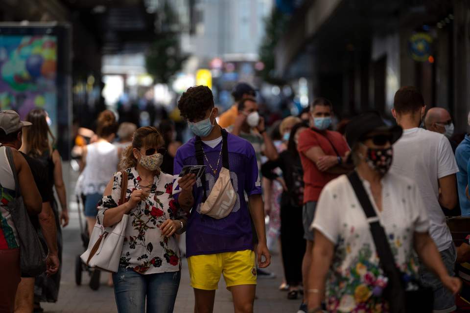 People wearing face masks walk in the centre of Madrid