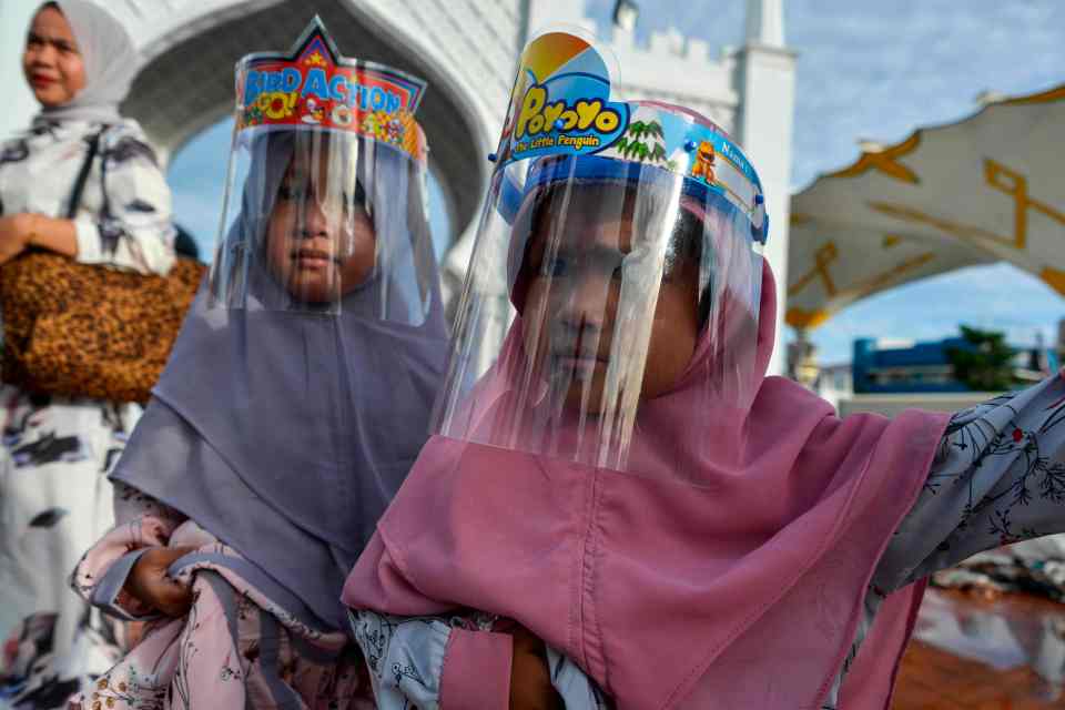 Two children with specially adapted protective masks for the taking part in Eid al-Adha