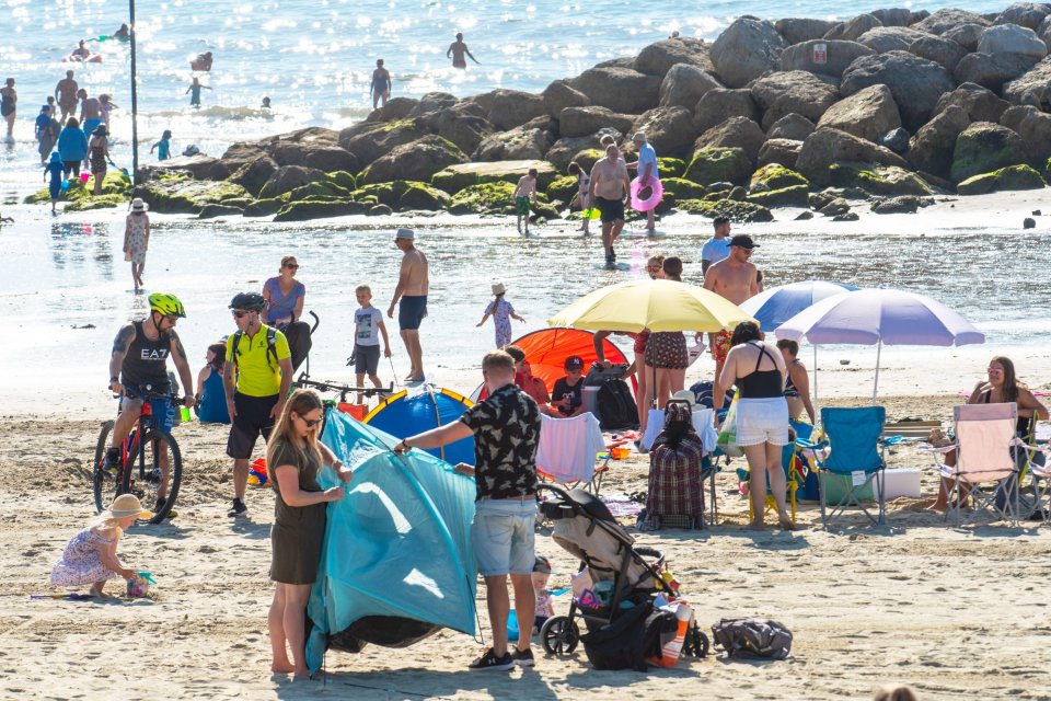 Families wrestle with beach tents and umbrellas