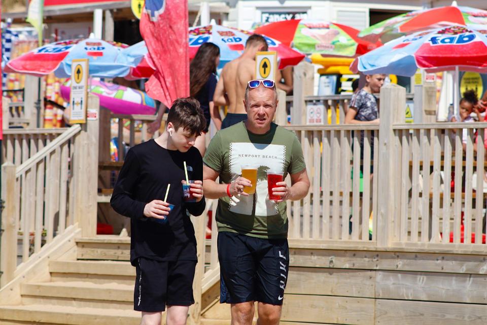 A man holds an ice cold pint of beer and cider while a youngster slurps on slushies