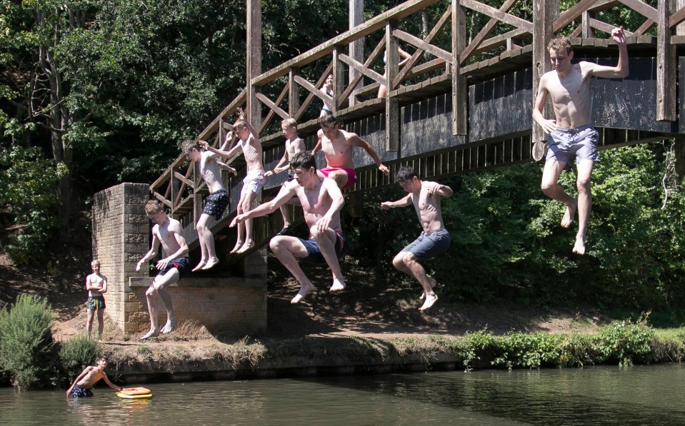 Lads jump into the River Wey as temperatures soar to 36C in Surrey town