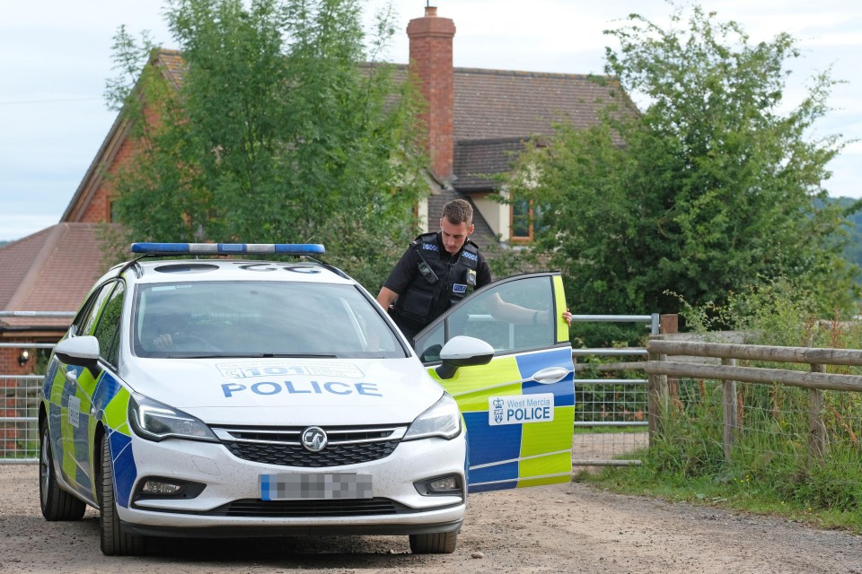 A cop walks through a gate at a farm in Mathon, Herefordshire where dozens of workers have coronavirus