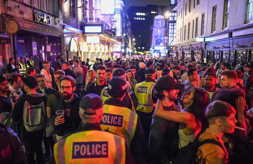 Police officers are seen walking through heavy crowds in Soho last night