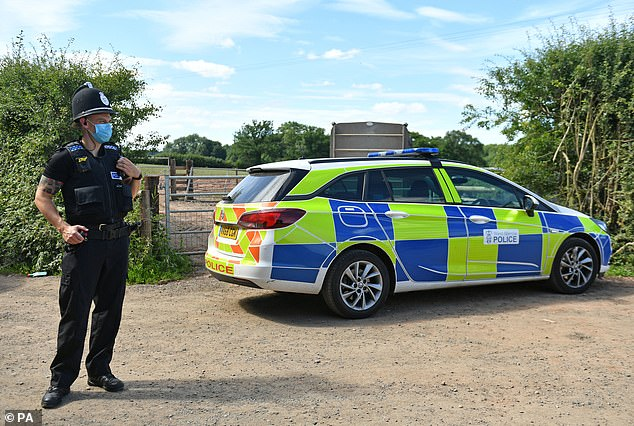 A cop wearing a protective mask guards a gate at the farm