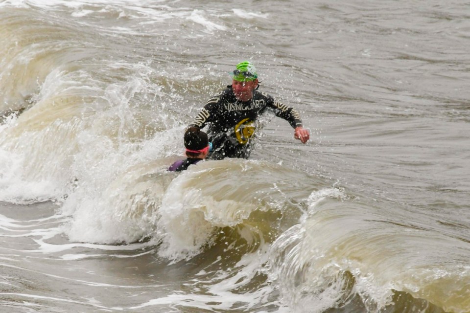 Brave swimmers venture into the sea amid choppy waves in West Bay, Dorset