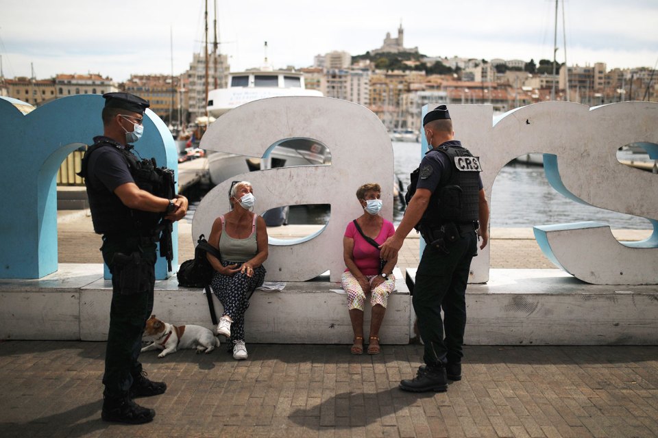 Gun-toting riot cops talk to residents wearing a mask in Marseille, southern France