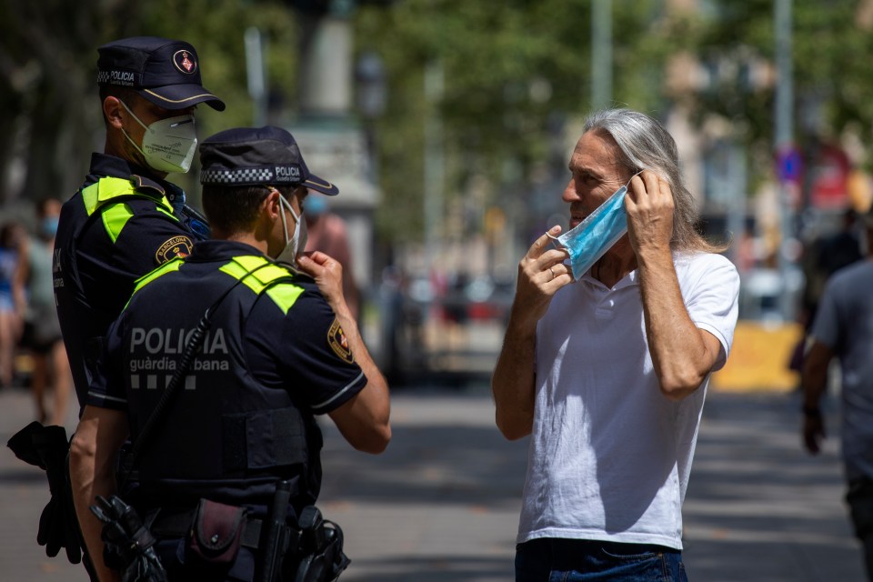 A man is stopped by police on Las Ramblas, Barcelona for not wearing his mask. Catalonia is one of the worst affected regions in Spain 