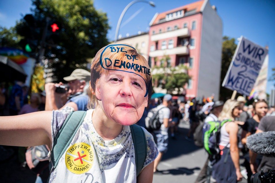 A woman wears an Angela Merkel mask with the inscription “Bye bye democracy” at the demonstration