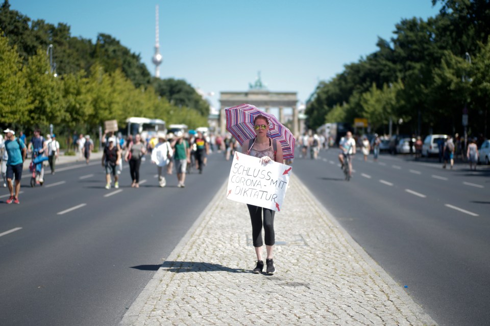 A woman carries a sign reading ‘End of the Corona dictatorship’ as she attends a protest near the Brandenburg gate