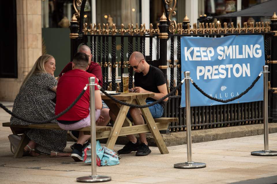 Drinkers at a bar in Preston city centre where tighter restrictions remain in place