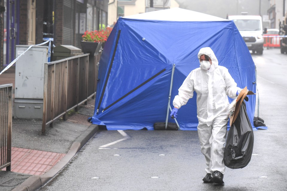 An officer carries evidence away in a bag