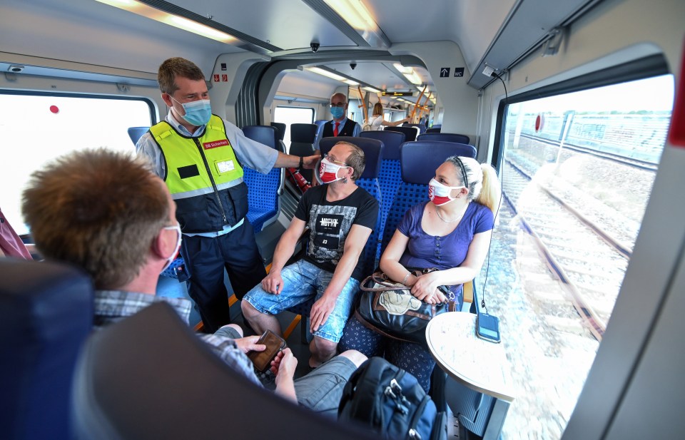 An inspector on a train in Germany checks if passengers' masks are covering their nose