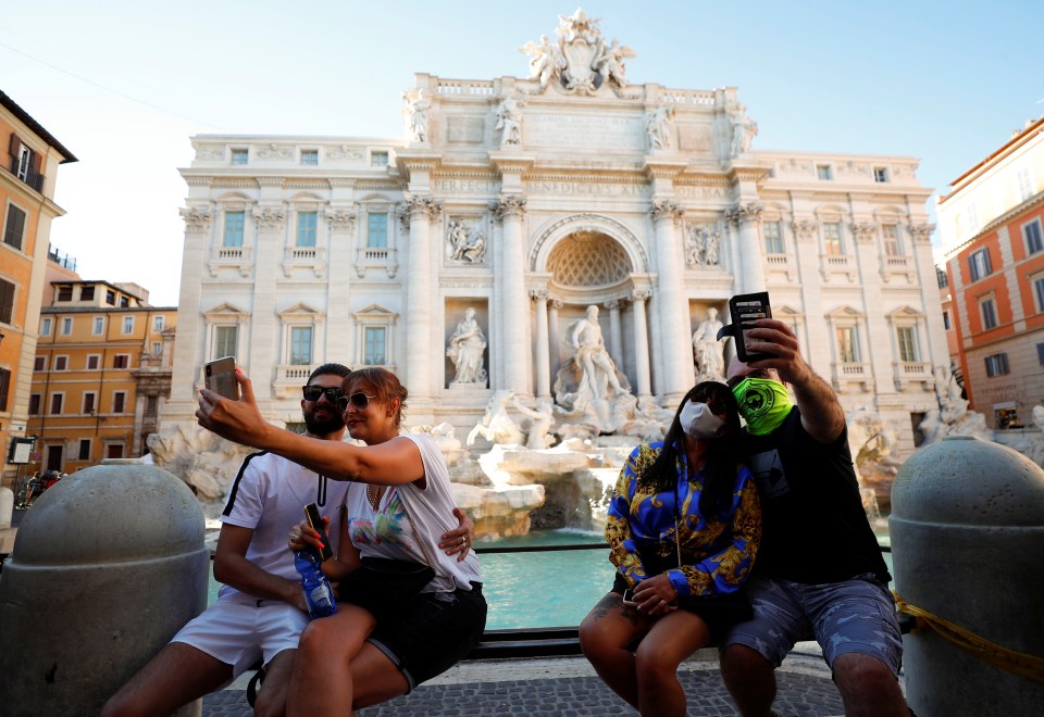 Tourists take selfies in front of the Trevi Fountain in Rome