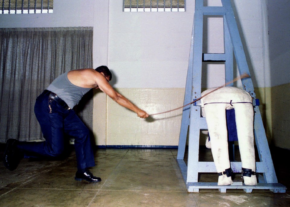 A prison officer demonstrates the caning procedure at Changi Prison