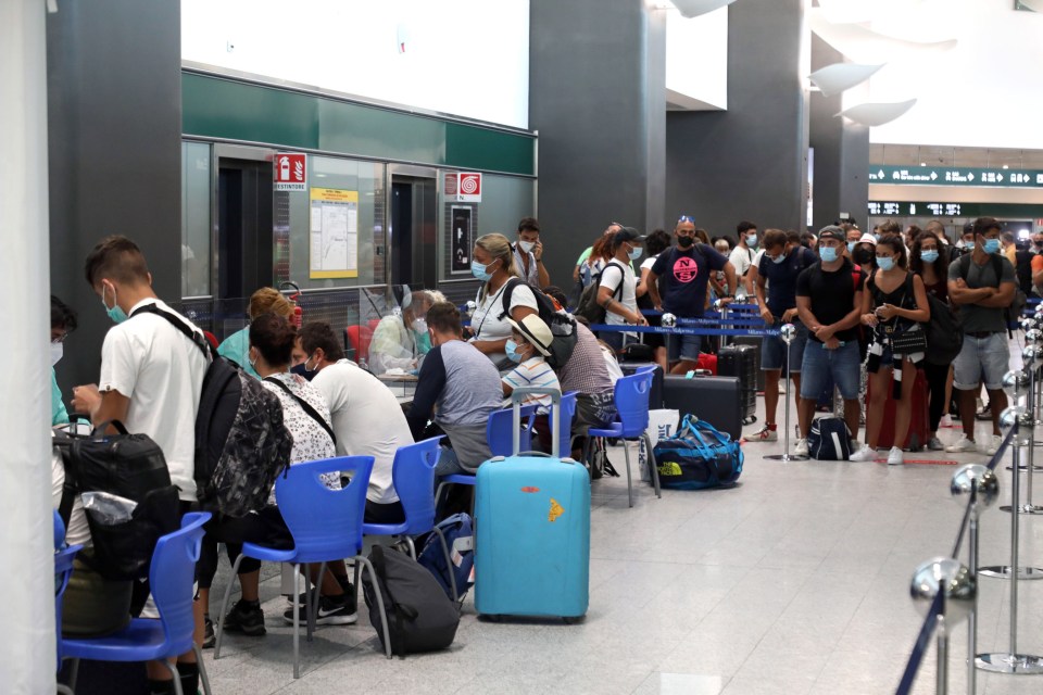 Health workers collect swabs and conduct tests on passengers for coronavirus at Malpensa airport in Milan