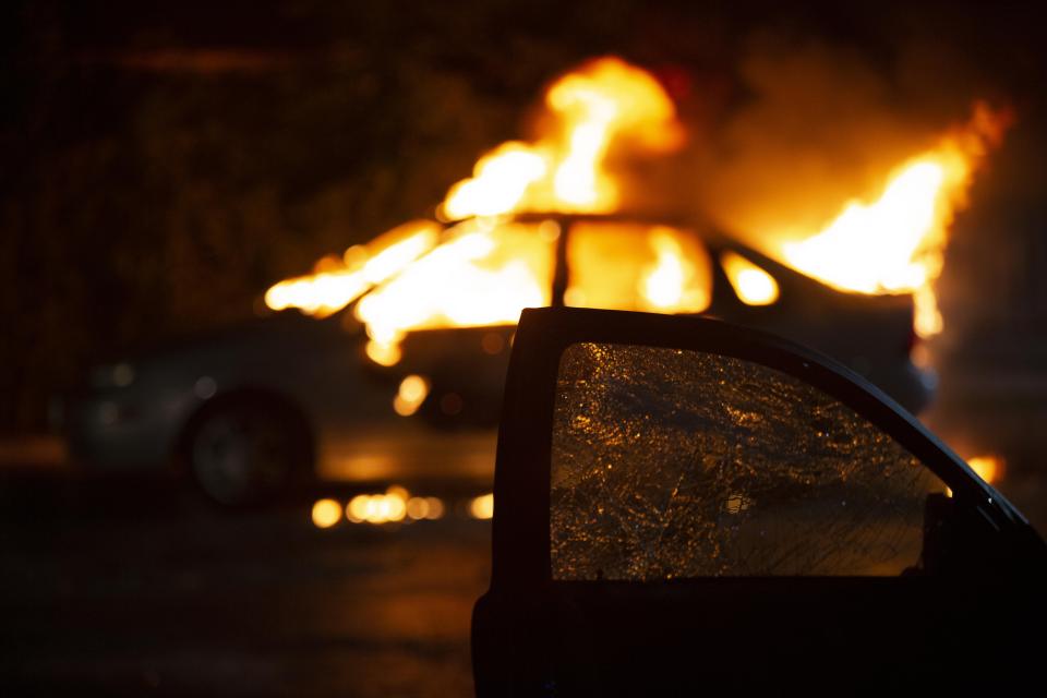 A vehicle burns after a car was set on fire in the lot where a man was shot in the head during the Kenosha protests