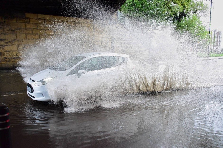 A car ploughs through water in Wallsend, North Tyneside as rain batters Britain