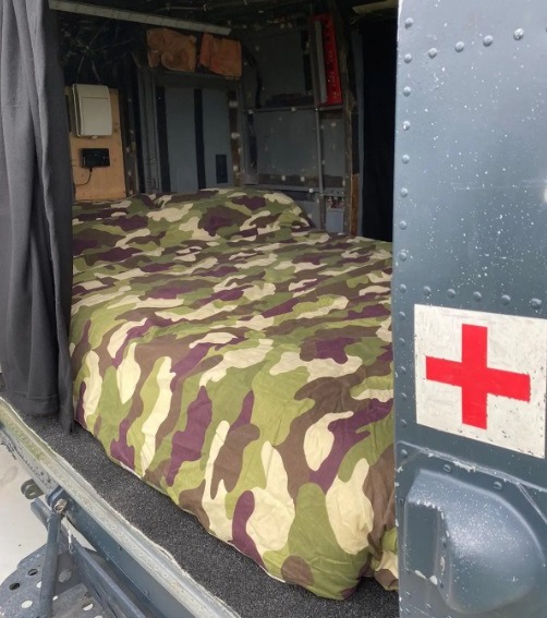 A double bed with camo bedding is inside the main cabin