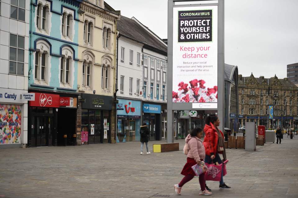 People walk past a sign advising them to socially distance in Newcastle