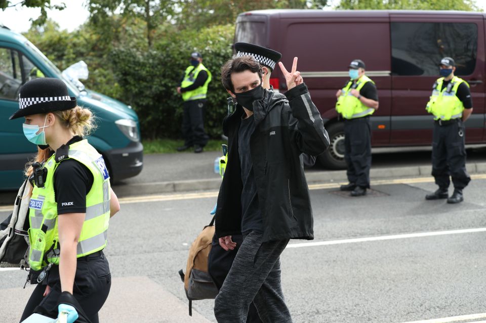 One man gives the peace sign as he is led away