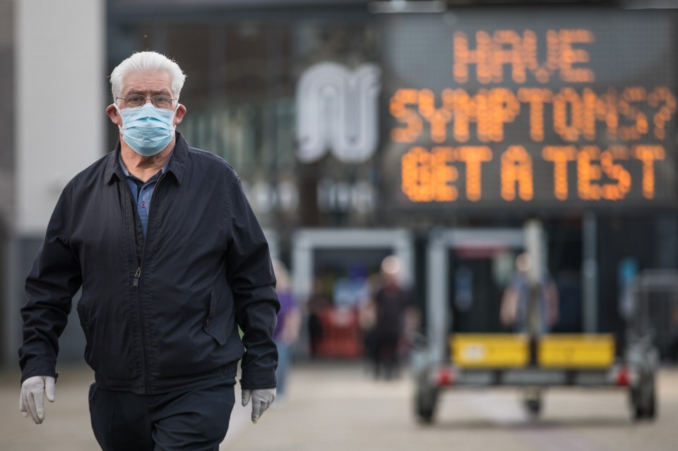 A man wears a mask as he walks through Bolton - where local restrictions are already in place