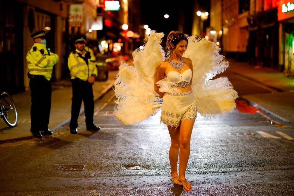 A party-goer wearing white feathers was one of the last to walk onto the street in Soho