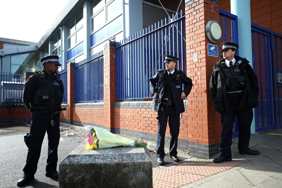 Officers stand guard outside the building where a colleague was shot dead