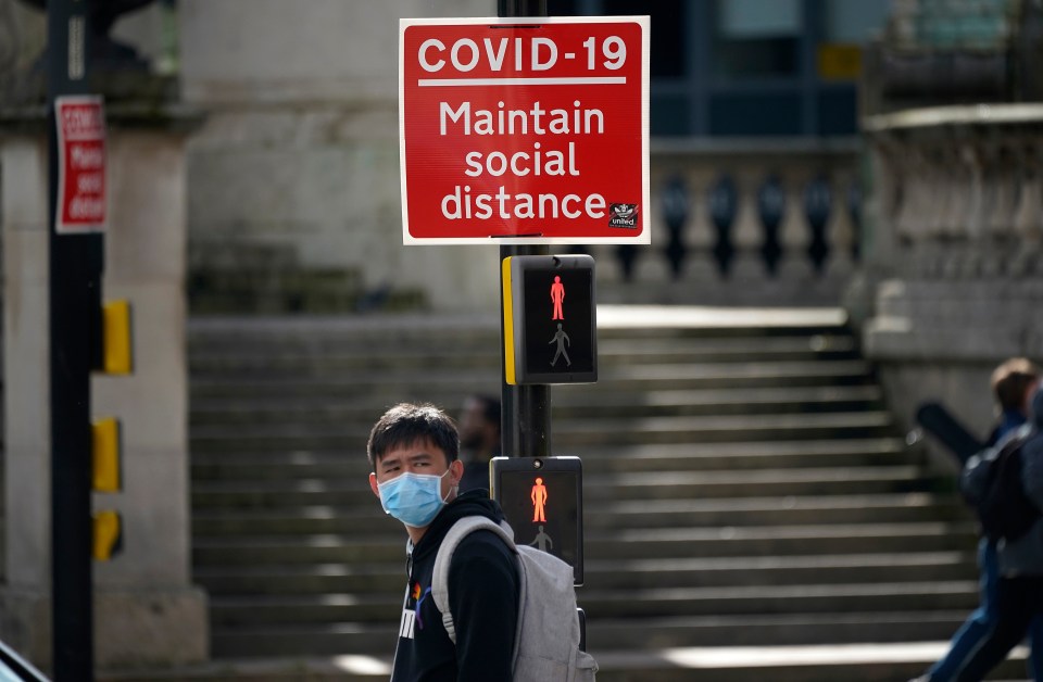 A social distancing sign is fixed next to a pedestrian crossing in Liverpool