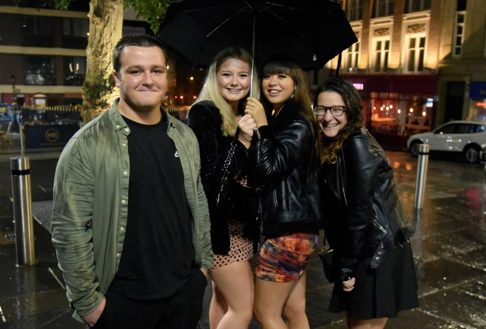 Friends huddle under an umbrella on a night out in Newcastle