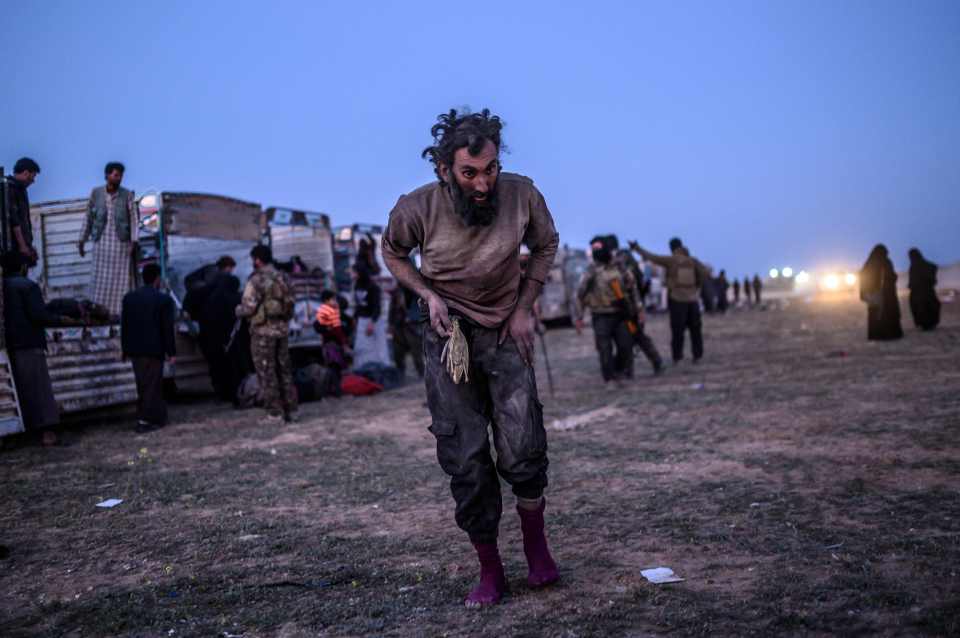 A suspected ISIS fighter walks past members of the SDF just after leaving  Baghouz