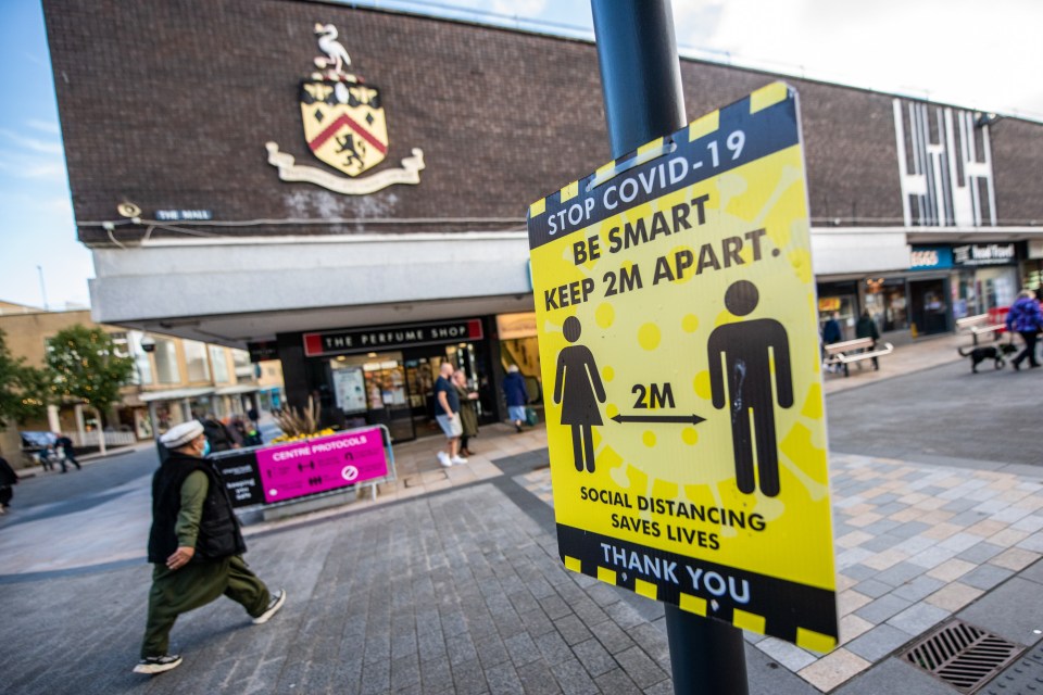 People walk past signs in Burnley, which is currently the UK's worst-hit area