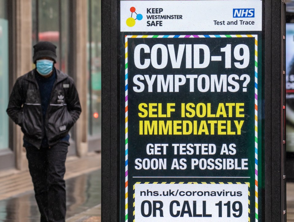 A man walks past an NHS sign in Westminster, London