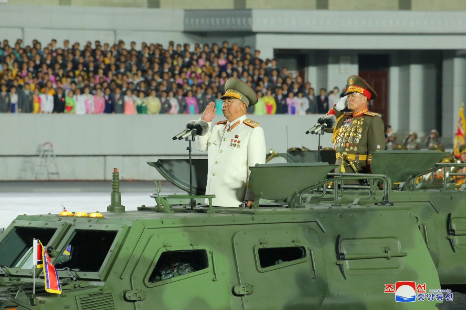 Senior officers saluting from military vehicles 