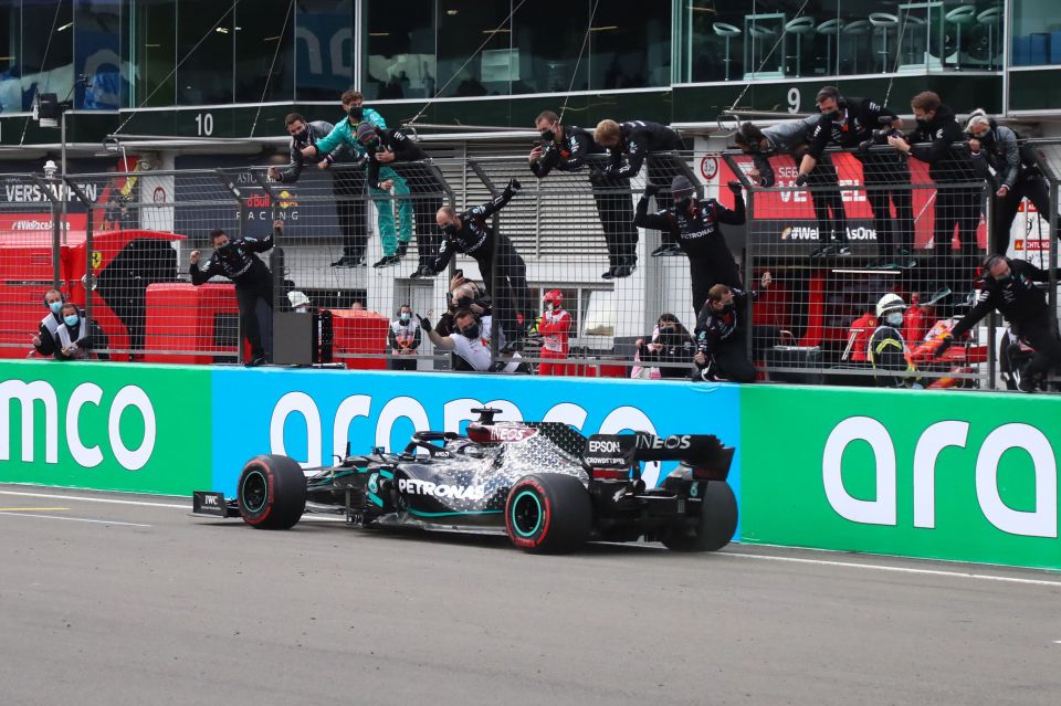 Lewis Hamilton is cheered on by his team as he crosses the line