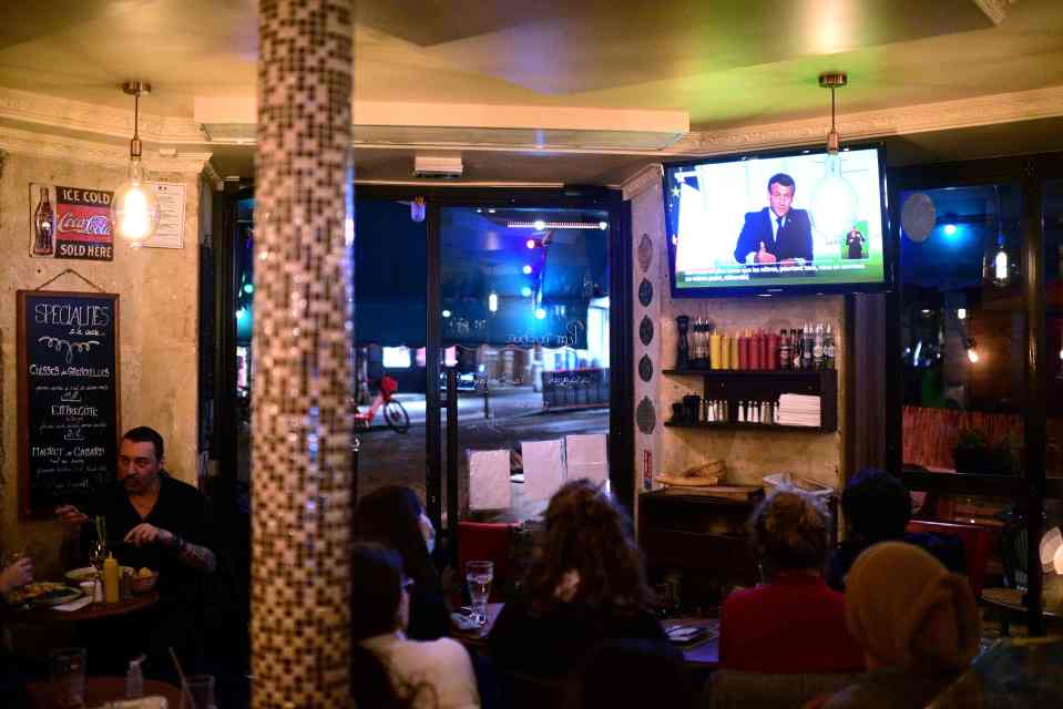 Parisians watch Emmanuel Macron deliver his TV address to the nation tonight as the country is plunged back into a national lockdown