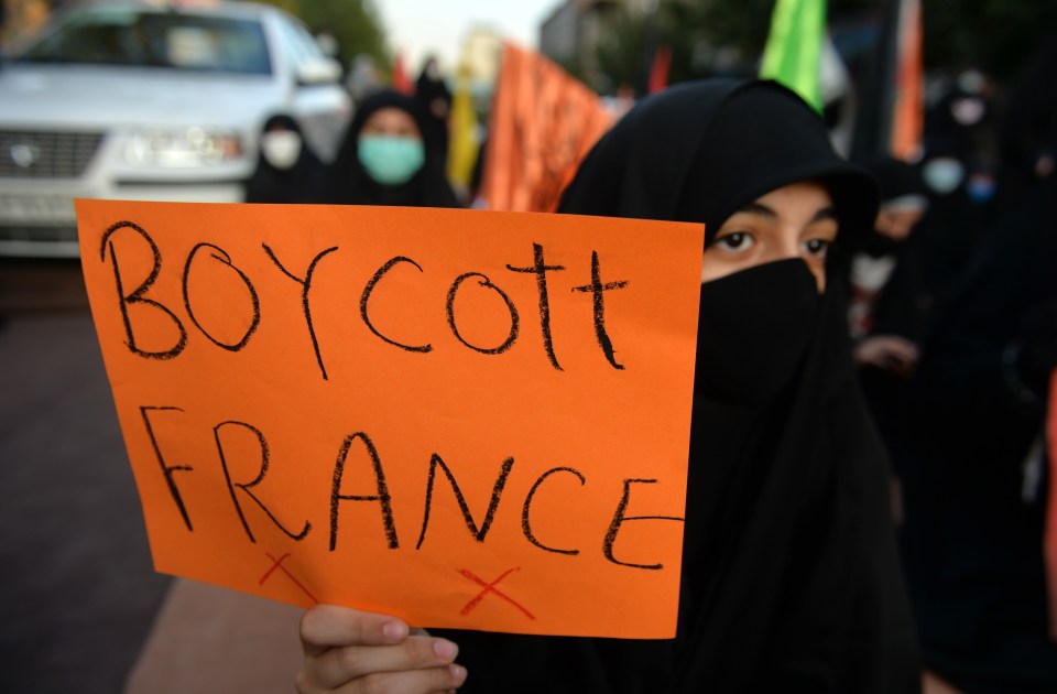 A woman holds a "Boycott France" sign outside the French embassy in Tehran