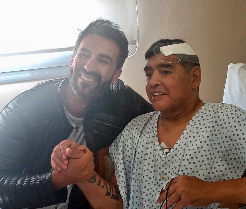 Maradona is seen shaking hands with his Leopoldo Luque after undergoing brain surgery 