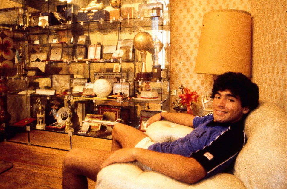 Maradona relaxes as he basks in the glow from his trophy stacked cabinet 