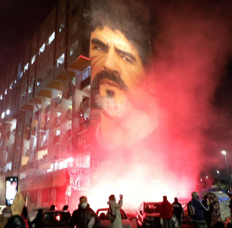 Napoli fans set off red smoke at a mural to their hero in the city