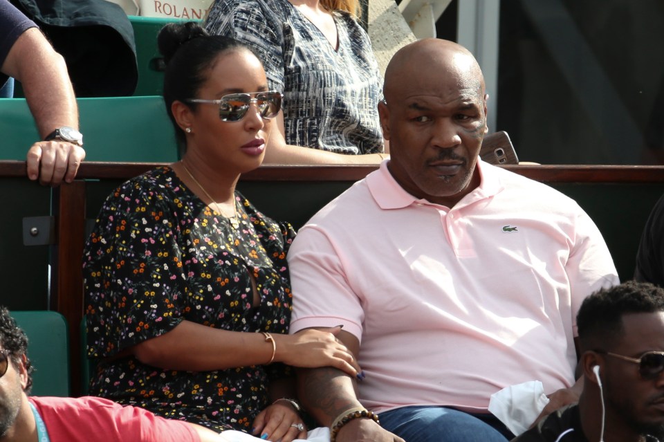 a man in a pink lacoste shirt sits next to a woman