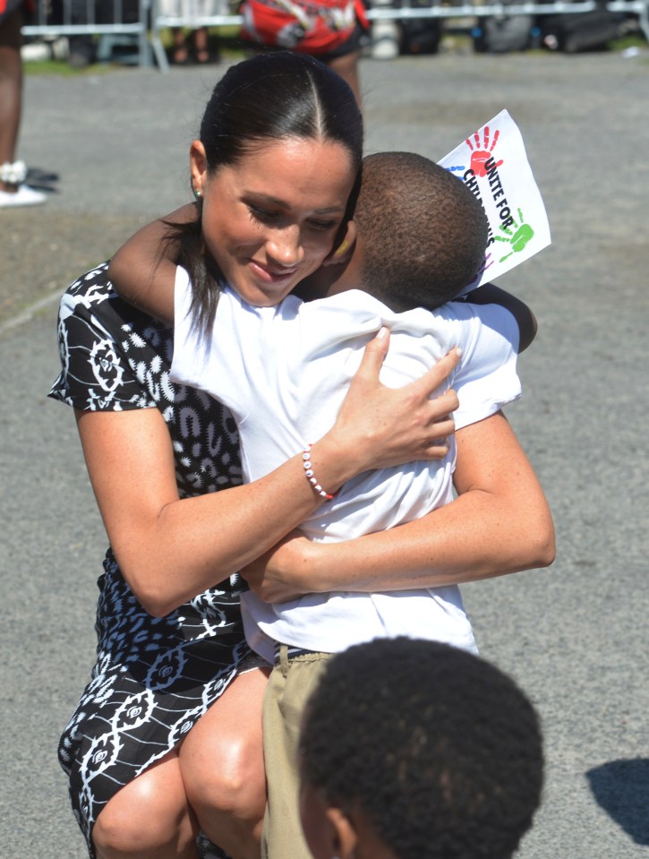 Meghan is seen hugging a child during her tour of South Africa with Prince Harry 