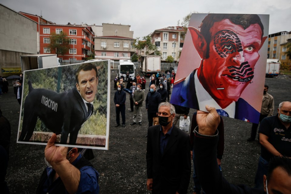 People hold posters with caricatures of France's President Emmanuel Macron in Istanbul