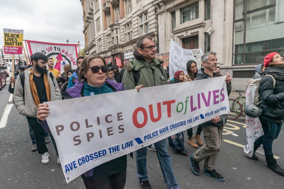 Demonstrators carrying a banner denouncing police spies in 2018