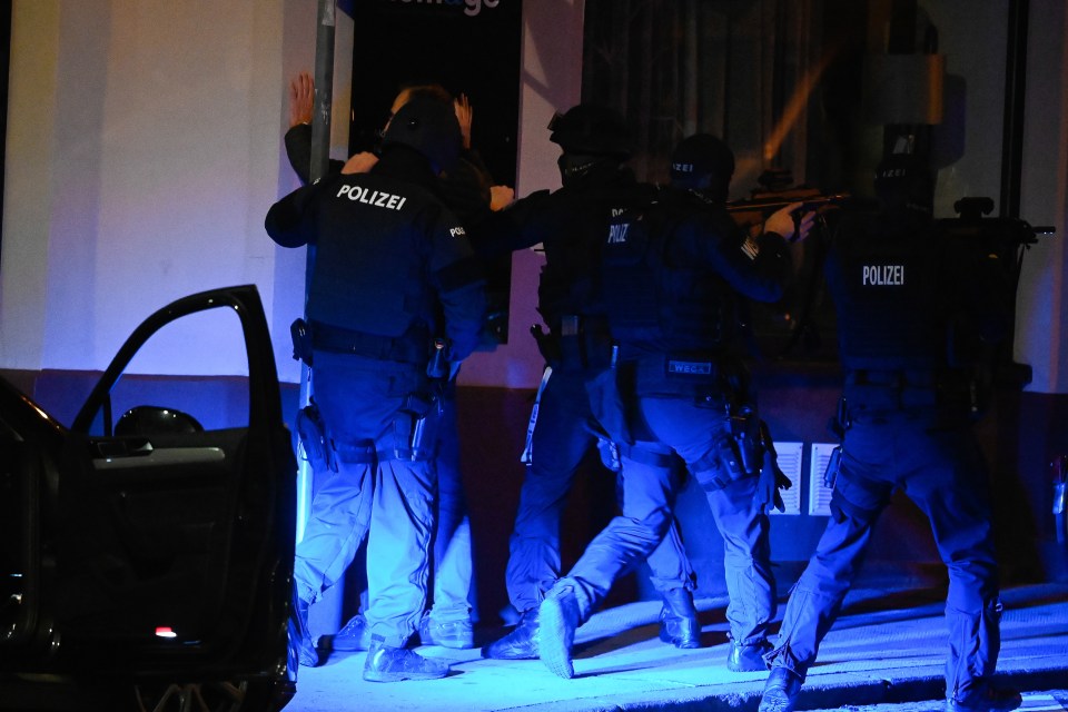 Armed cops search a man near the scene of the attack